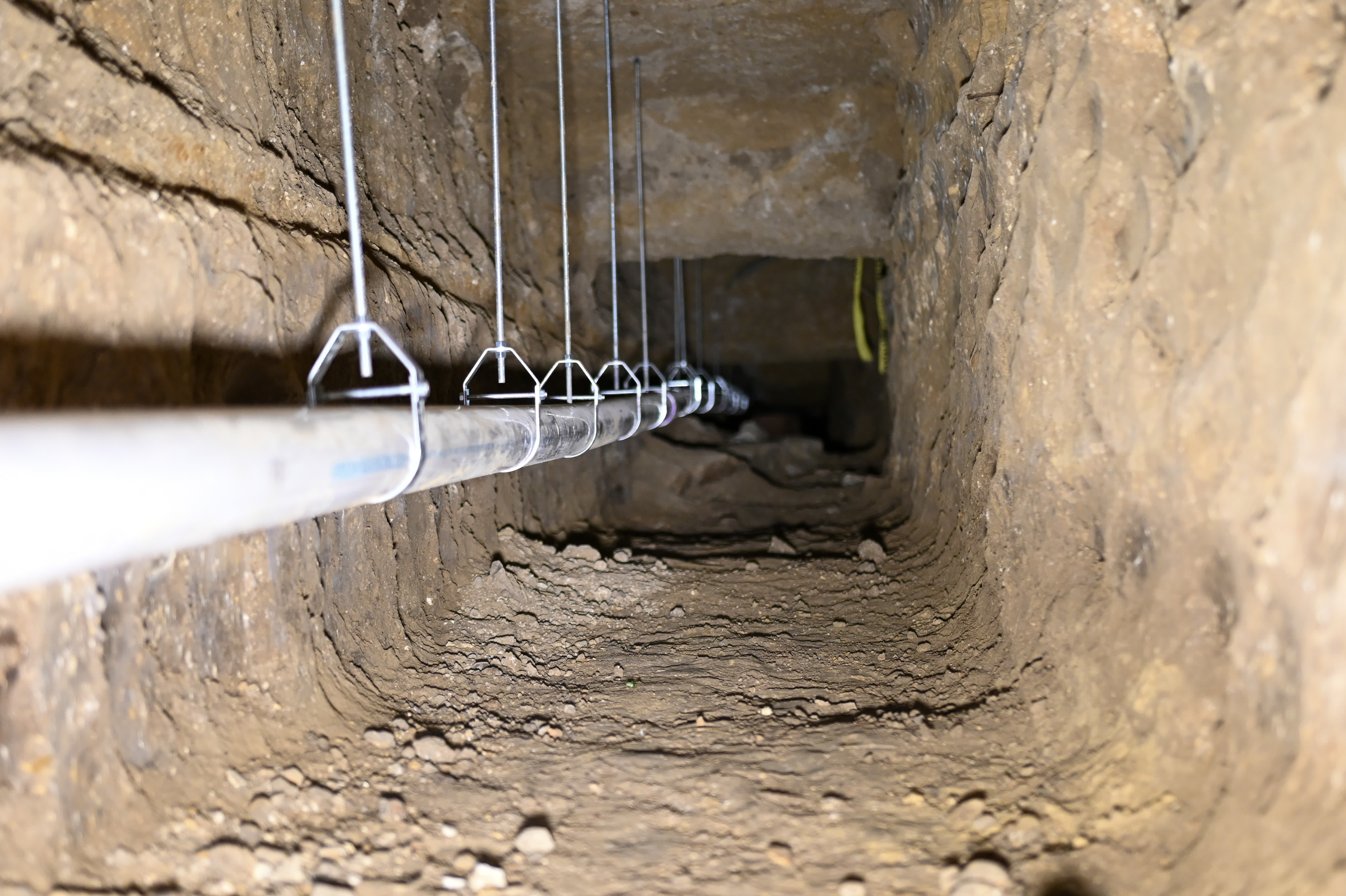 Water line on wire hangers inside a tunnel dug to reach an under-slab line
