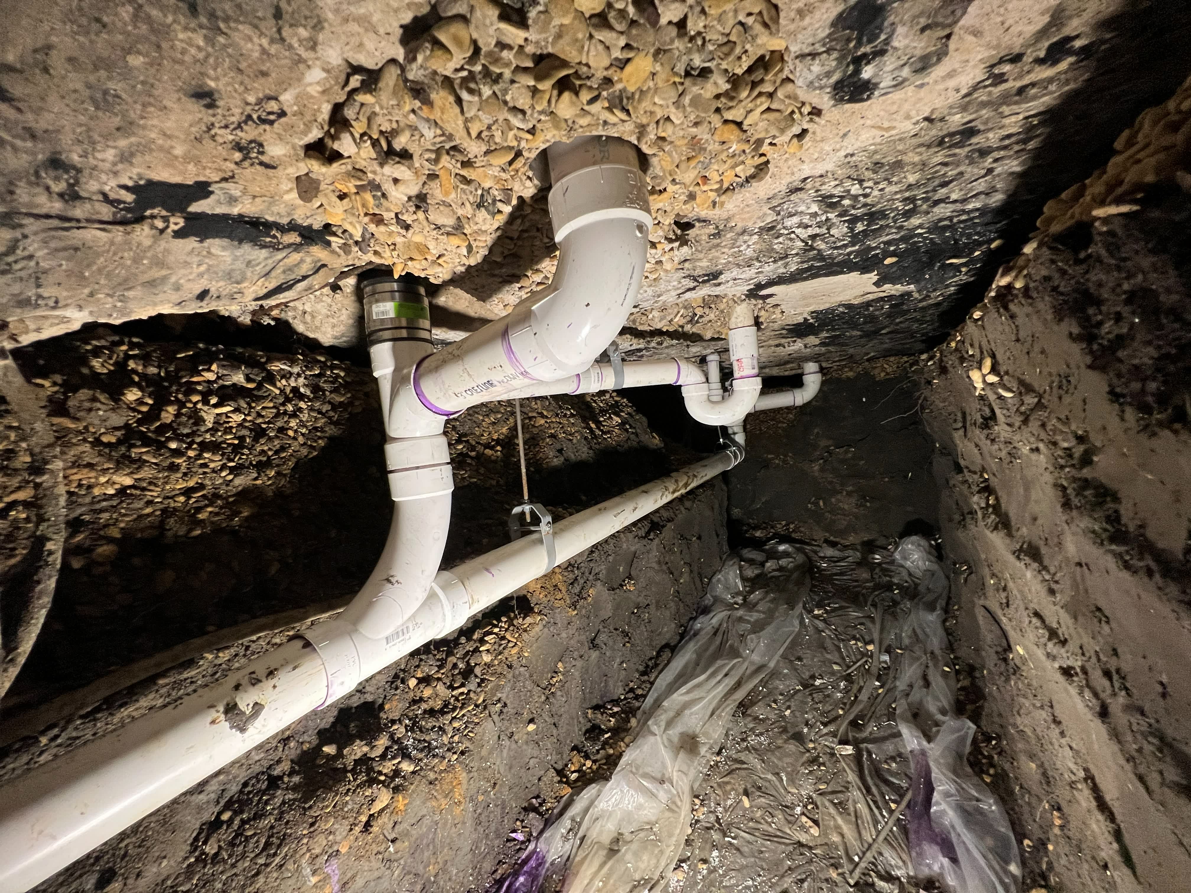 New PVC drain line installed in a tunnel dug beneath a home foundation