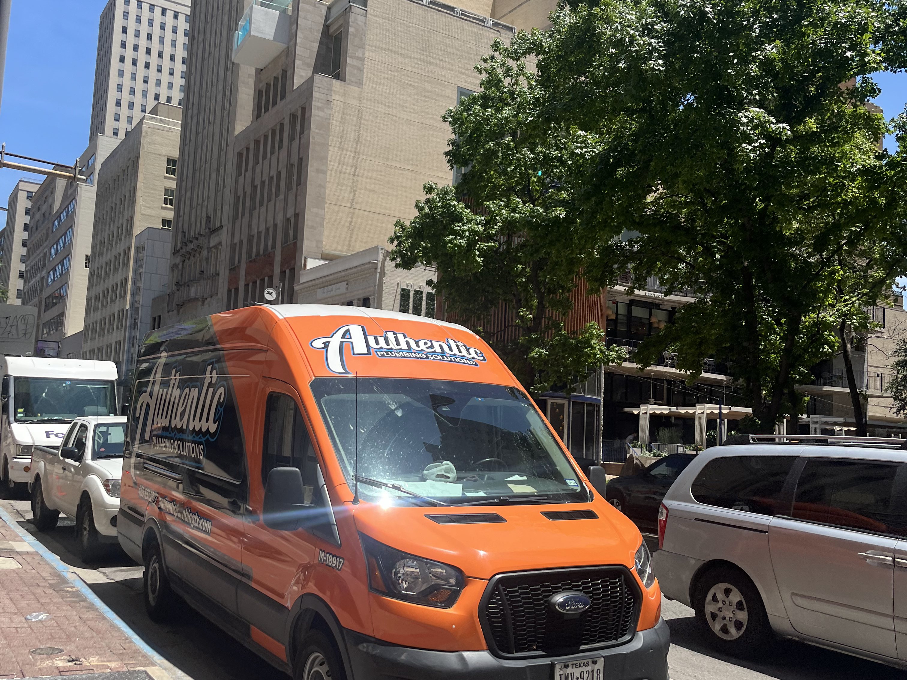 Authentic Plumbing Solutions van on a street in downtown Dallas