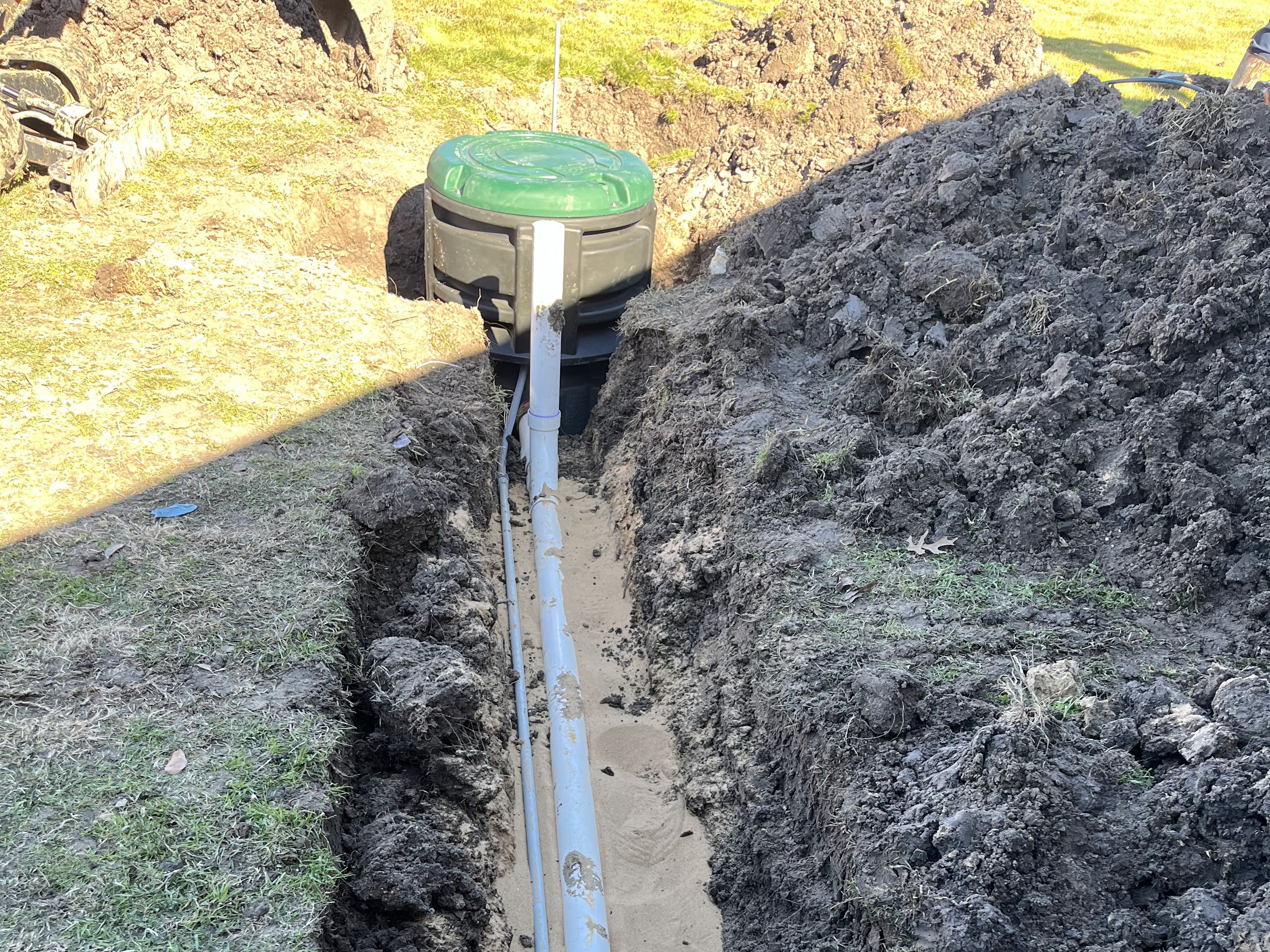 New sewer line and cleanout riser set in an open yard trench
